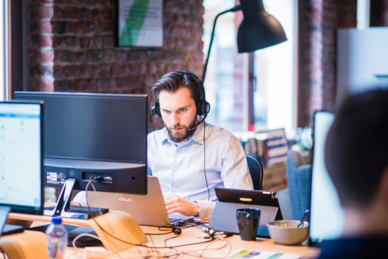 man on headset at desk looking at computer