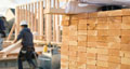 lumber at a construction site with worker moving a piece