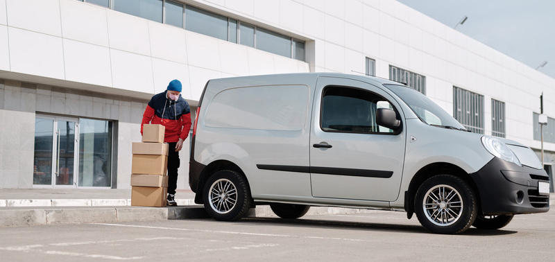 Delivery Man With Boxes next to a White Van