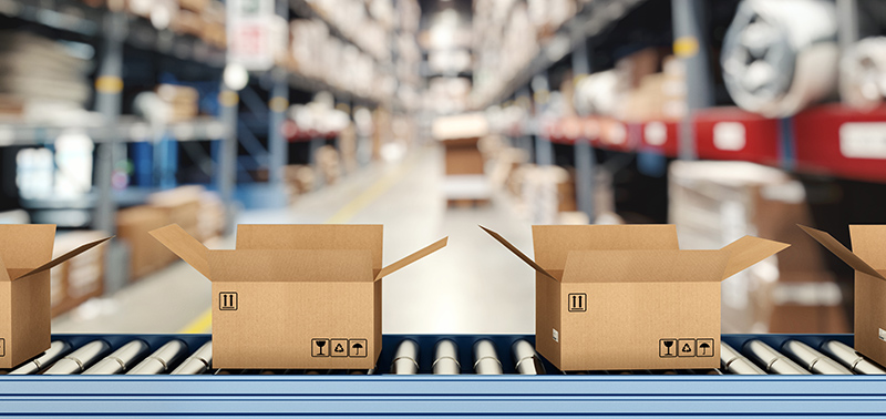 Cardboard boxes on conveyor roller with racks on background