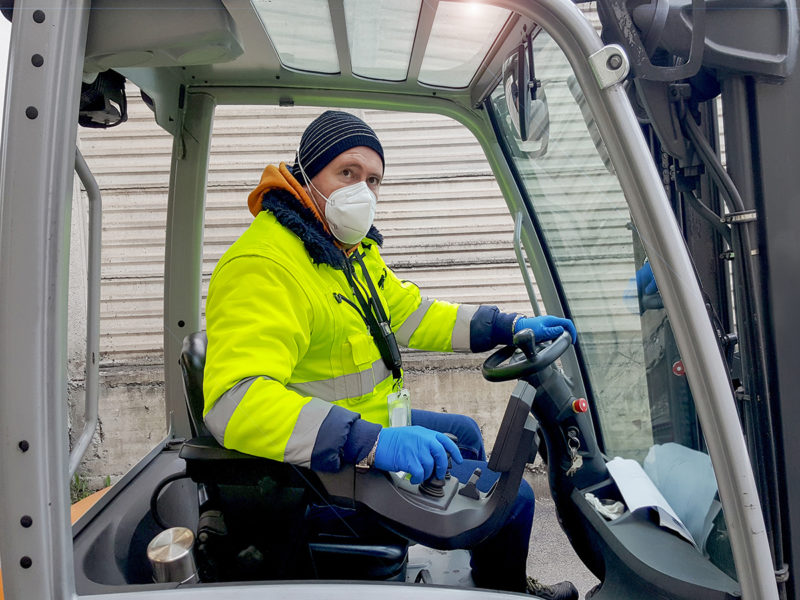 coronavirus : man with protective mask and gloves drives the forklift