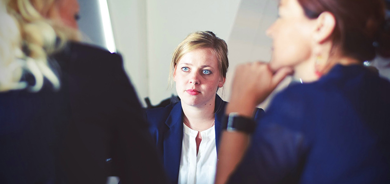 three women in dark suits having business discussion