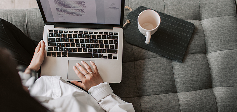 Canva - Crop woman using laptop on sofa at home