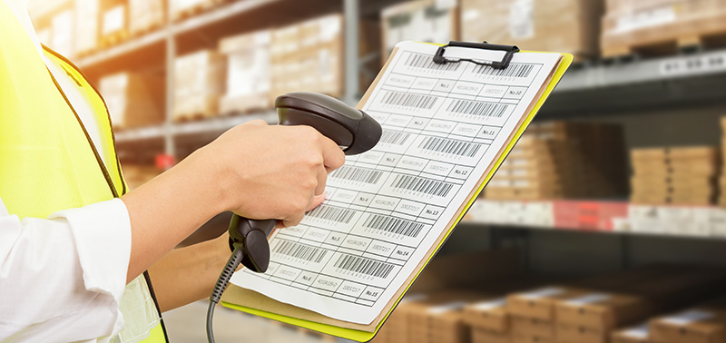 Worker checking and scanning package by laser barcode scanner in modern warehouse.