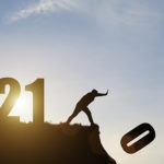 Man push number zero down the cliff where has the number 2021 with blue sky and sunrise. It is symbol of starting and welcome happy new year 2021.