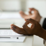 African american calm businessman relaxing meditating in office, peaceful ceo in suit practicing yoga at work, focus on black man hands in mudra, successful mindful people habits concept, close up