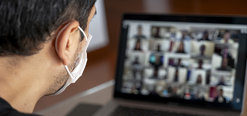 Man using a mask and having a video conference with work team am