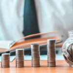 Financial businessman with coins put in a jar, Saving money for future growth and knowing how to manage your spending wisely, Saving money for business growth or long-term profitability.