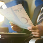 Crop portrait of modern bearded businessman reading documents and working while enjoying flight in first class, copy space