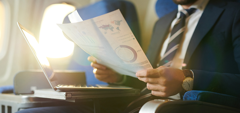 Crop portrait of modern bearded businessman reading documents and working while enjoying flight in first class, copy space