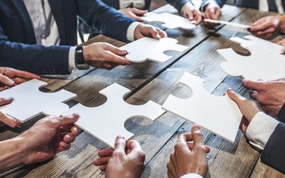 Business people and puzzle on wooden table, teamwork concept