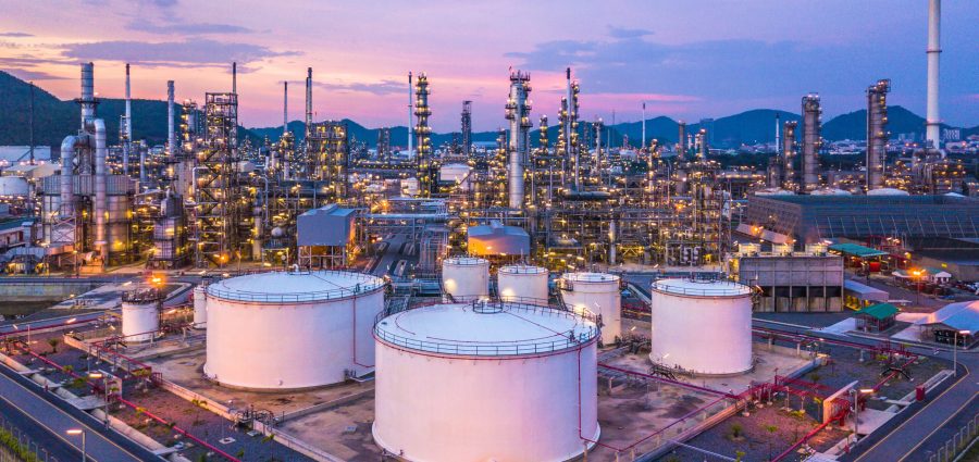 Aerial top view oil and gas chemical tank with oil refinery plant background at twilight.