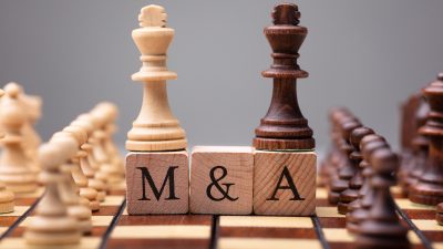 Close-up Of King Chess Pieces On Wooden Blocks With Mergers And Acquisitions