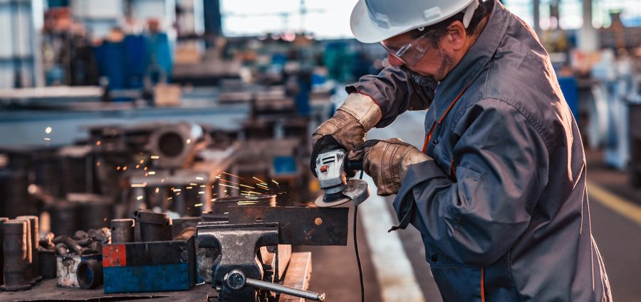 Skilled industrial worker grinding metal part.