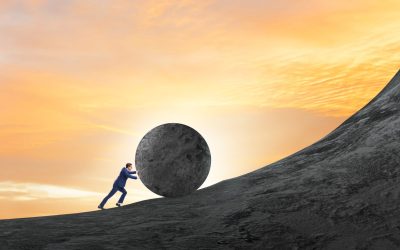 Man pushing large stone to the top