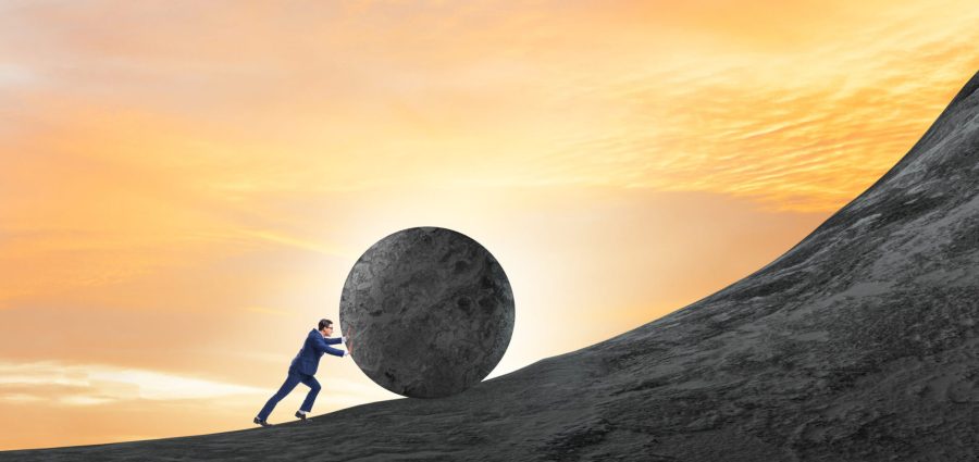 Man pushing large stone to the top