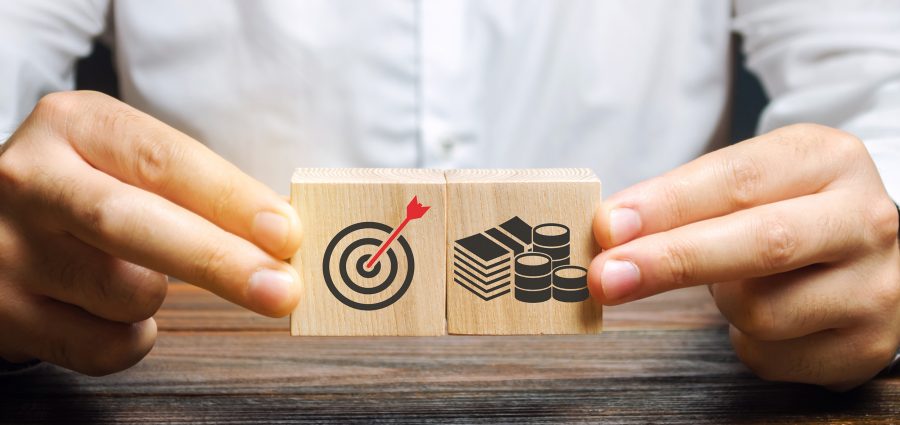 Businessman collects wooden blocks with the image of the goal and money. The concept of doing business and finance. Setting goals and objectives for maximum profit. Strategy and Planning