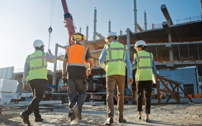 Diverse Team of Specialists Inspect Commercial, Industrial Building Construction Site. Real Estate Project with Civil Engineer, Investor and Worker. In the Background Crane, Skyscraper Formwork Frames