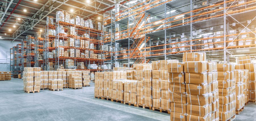 Large industrial warehouse with high racks. In the foreground are a lot of cardboard boxes. Overloaded warehouse building.