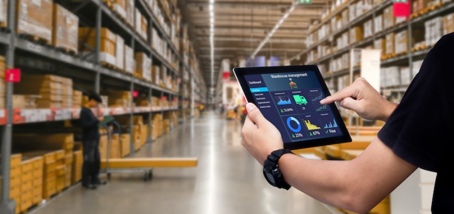 Smart warehouse management system.Worker hands holding tablet on blurred warehouse as background