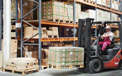 warehouse worker driver in uniform delivery and loading cardboxes by forklift stacker loader