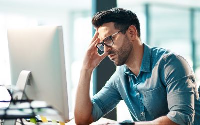 Stress, headache and frustrated business man working on computer in an office, annoyed and anxious. Male under pressure from a workload and deadline. Depressed guy experiencing burnout at work.