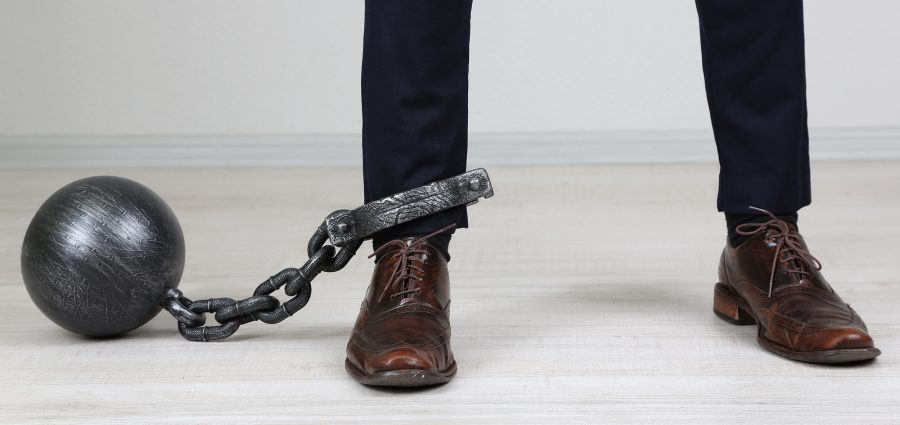 Business worker with ball and chain attached to foot