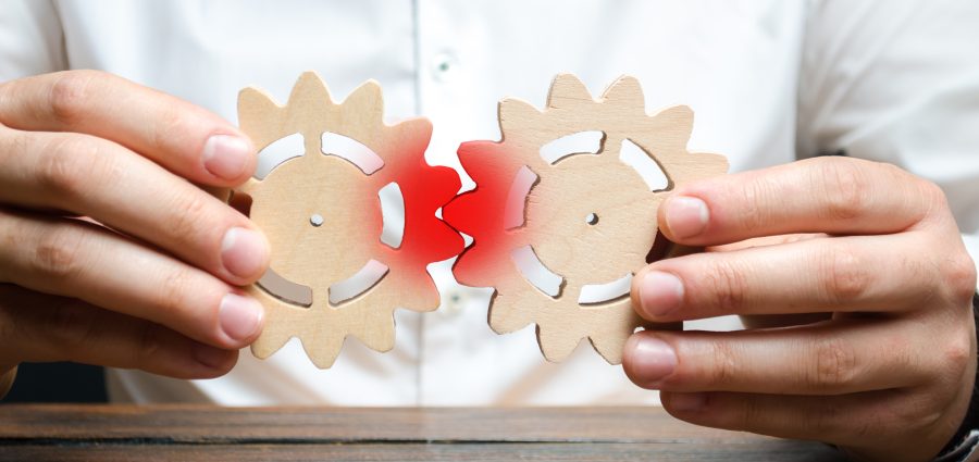 A businessman tries to put two gears together and fails to make them work. The concept of the impossibility of effective business processes, high costs and low returns. Wrong business model.