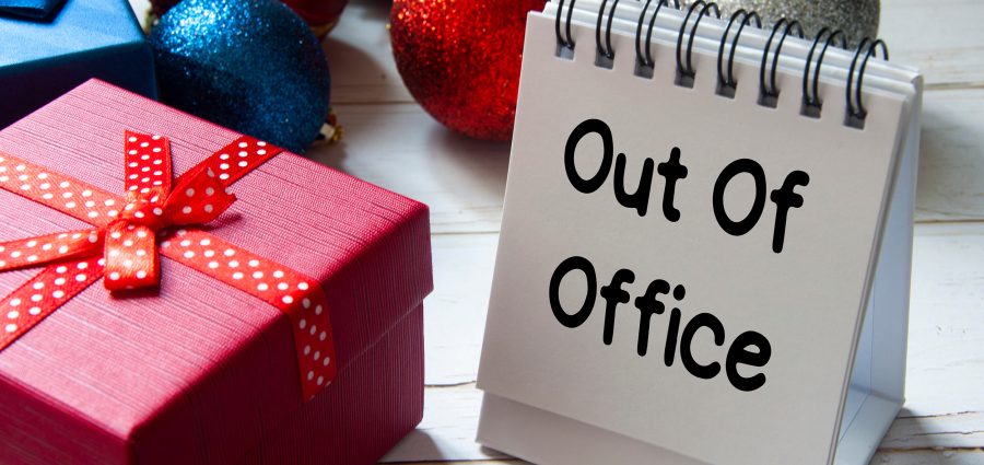 Out of office text on notepad with Christmas decoration. Holiday concept.