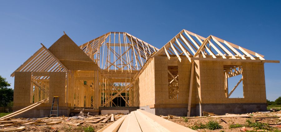 A new home being built with wood, trusses, supports and a foundation.