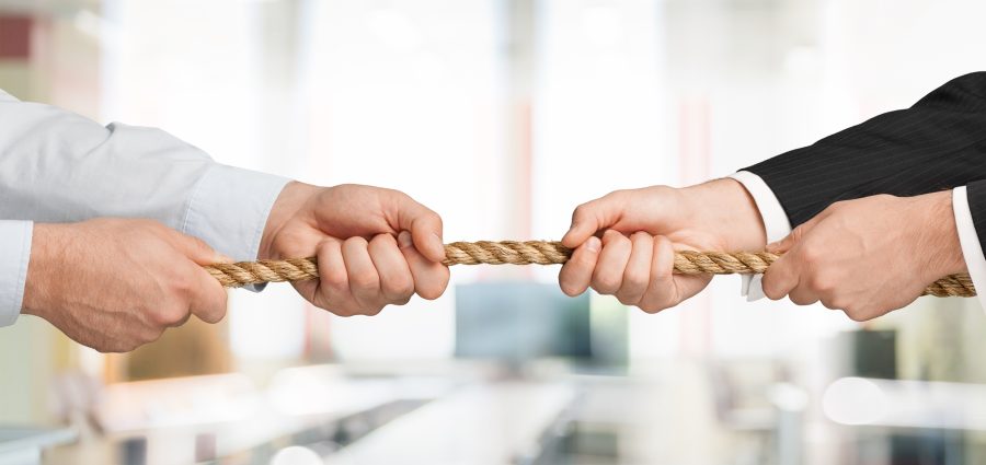 Business people pulling rope in opposite directions at office