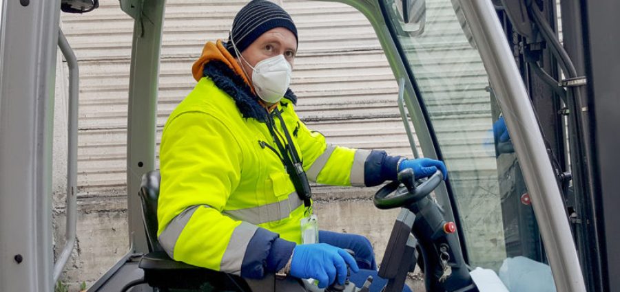 coronavirus : man with protective mask and gloves drives the forklift