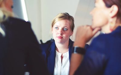 three women in dark suits having business discussion