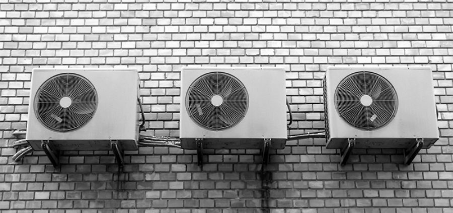 three air conditioning units on a white brick wall