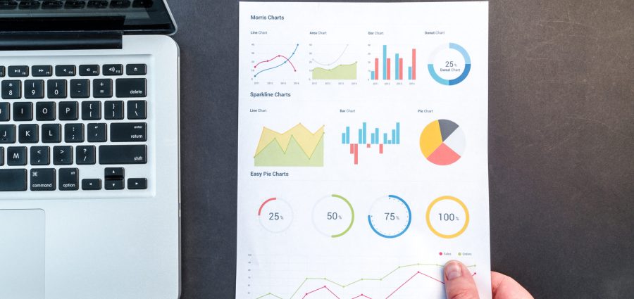 Notebook with charts next to a laptop