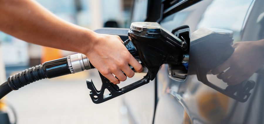 Closeup of woman pumping gasoline fuel in car at gas station. Petrol or gasoline being pumped into a motor. Transport concept