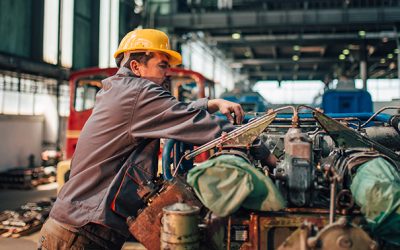 Train mechanic working on engine at heavy industry factory.