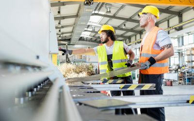 Male manual workers manufacturing sheet metal at industry