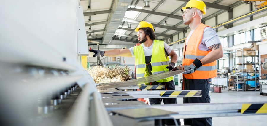 Male manual workers manufacturing sheet metal at industry