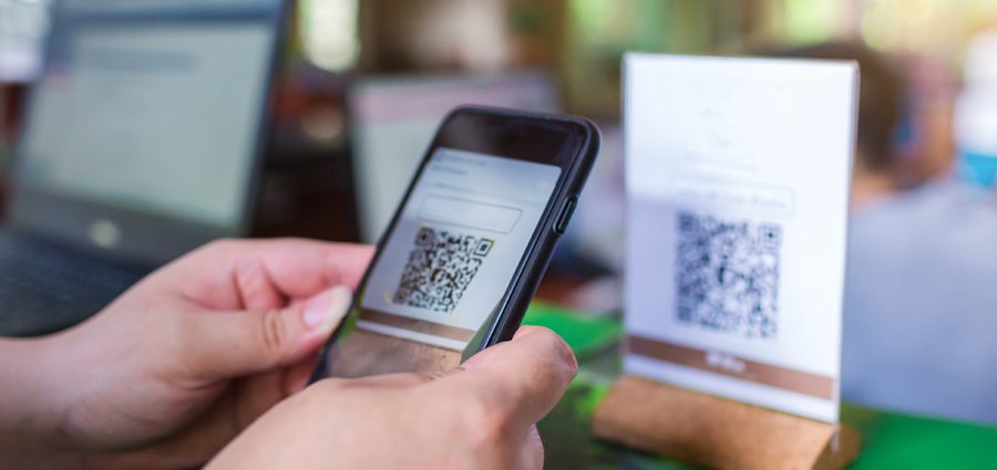 Closeup of a hand holding phone and scanning QR code with blurry