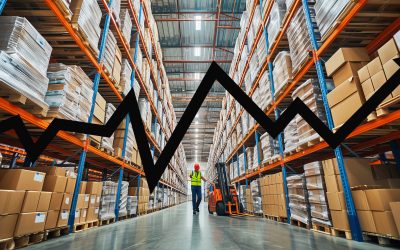 Warehouse worker walking with a forklift in a large warehouse full of shelves