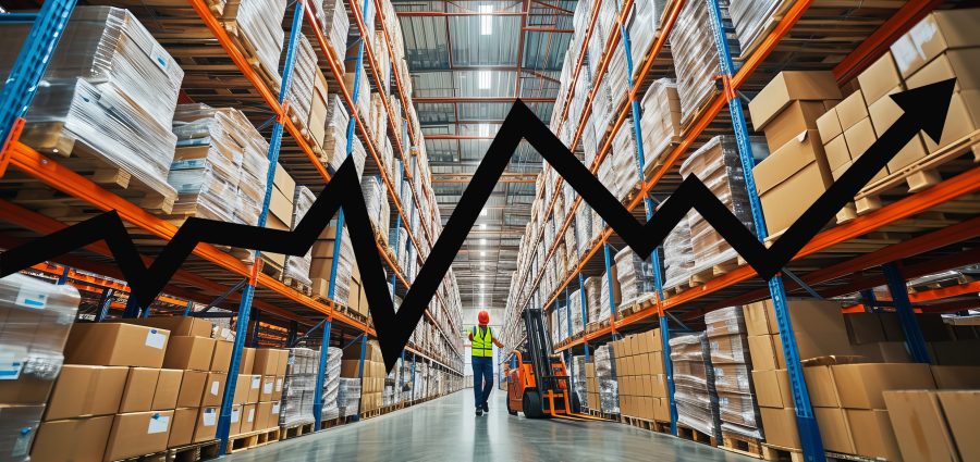 Warehouse worker walking with a forklift in a large warehouse full of shelves