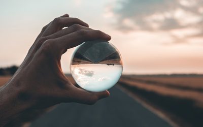 man holding crystal ball over a road at sunset