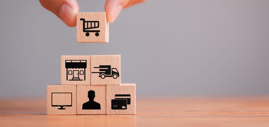 Concept add to cart, Online shopping, ecommerce and delivery service. The hand holds a wooden cube with icons - trolley, market, delivery, computer, customer and payment. Close up.