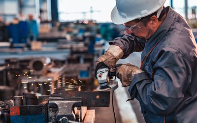 Skilled industrial worker grinding metal part.