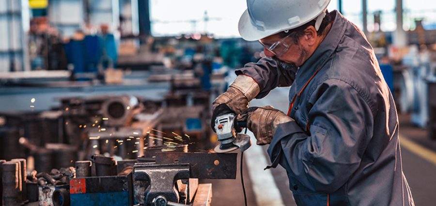 Skilled industrial worker grinding metal part.