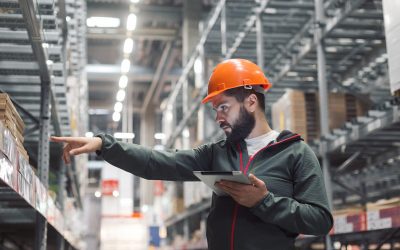 Warehouse manager checking his inventory in a large warehouse. using the tablet via the Internet is checking stock availability