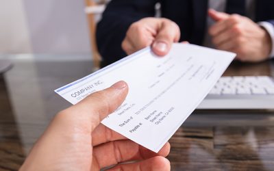 Close-up Of A Businessperson's Hand Giving Cheque To Colleague At Workplace