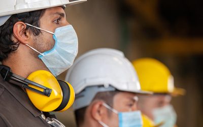 Workers wear protective face masks for safety in machine industrial factory.