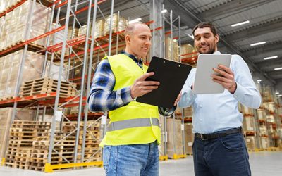 wholesale, logistic business and people concept - warehouse worker and businessman with clipboard and tablet pc computer